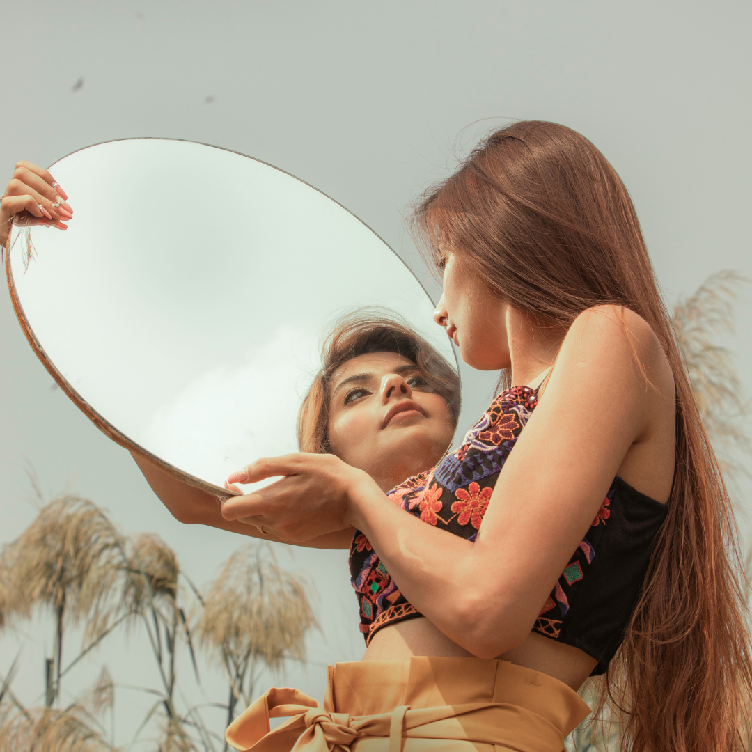 Arty photo of women looking at alternative self in mirror 